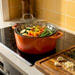 Steamer basket with vegetables in kitchen